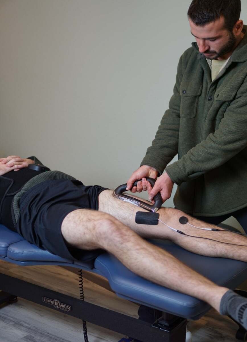 Clinician performing instrument-assisted soft tissue work on a patient's shoulder at The ChiropractOrr in Campbell