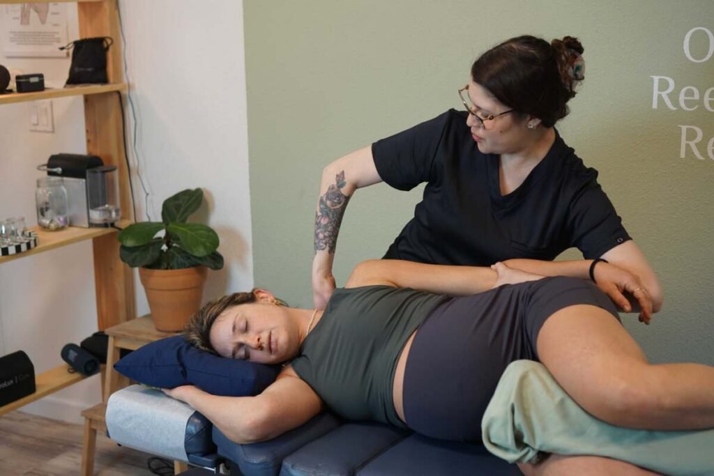 Massage therapist applying myofascial release and deep tissue massage to a patient's lower back at The ChiropractOrr